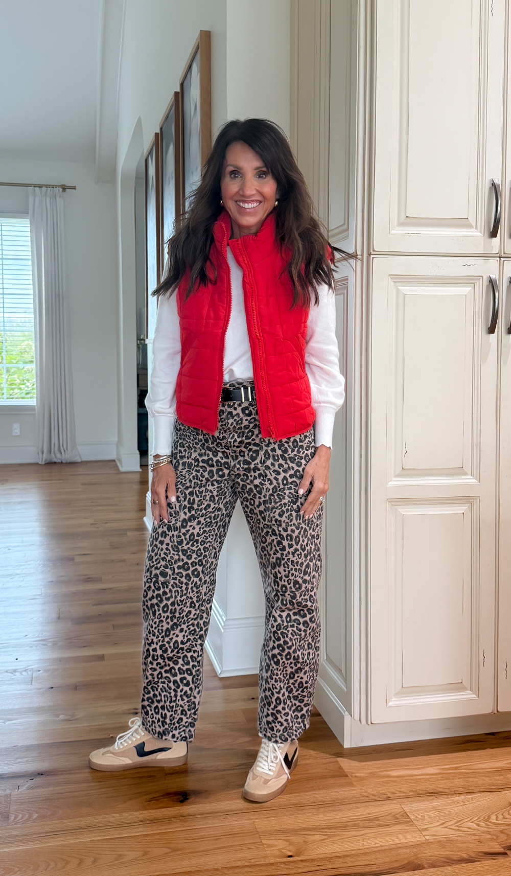Red Amazon quilted vest paired with leopard print pants and a white sweater, styled with sneakers for a fun fall outfit idea.