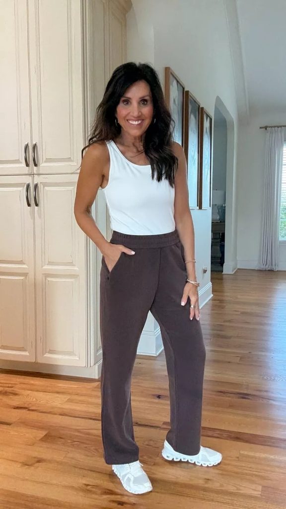 Cyndi wearing a white tank top with brown wide leg lounge pants and white sneakers, a simple fall athleisure outfit that’s comfortable and stylish.