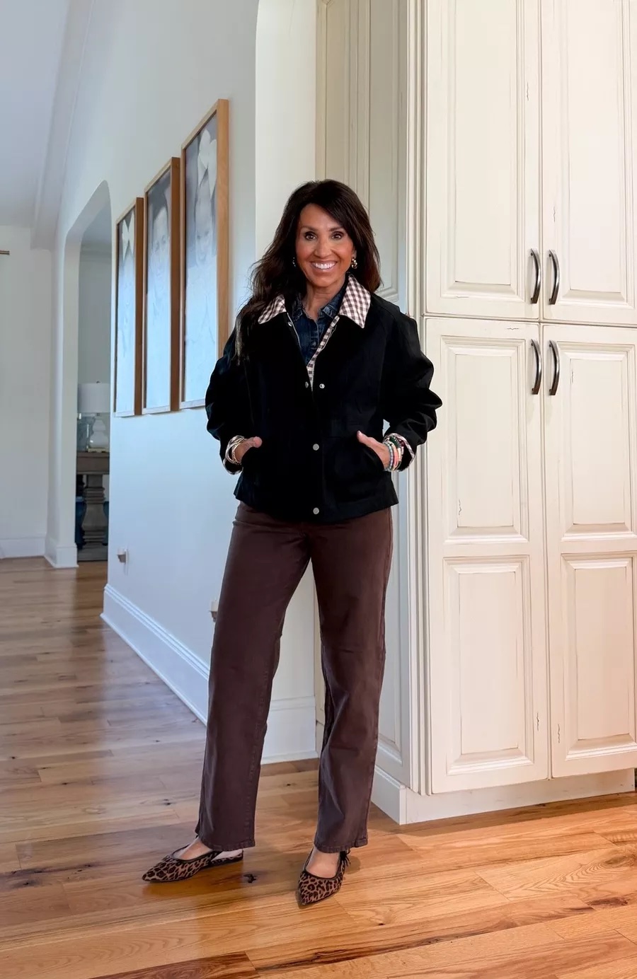 Cyndi Spivey wearing a black barn-style jacket with a checked collar, brown pants, and leopard flats for a casual fall look.