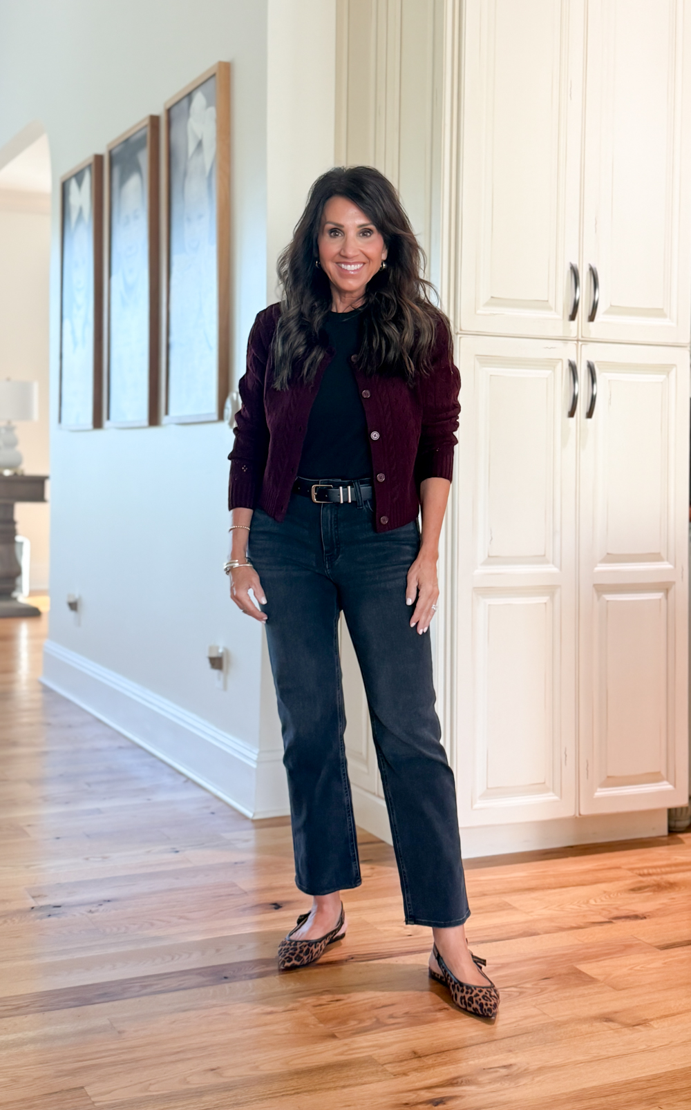 Cyndi Spivey wearing black straight leg jeans, black top, burgundy cardigan, and leopard flats.