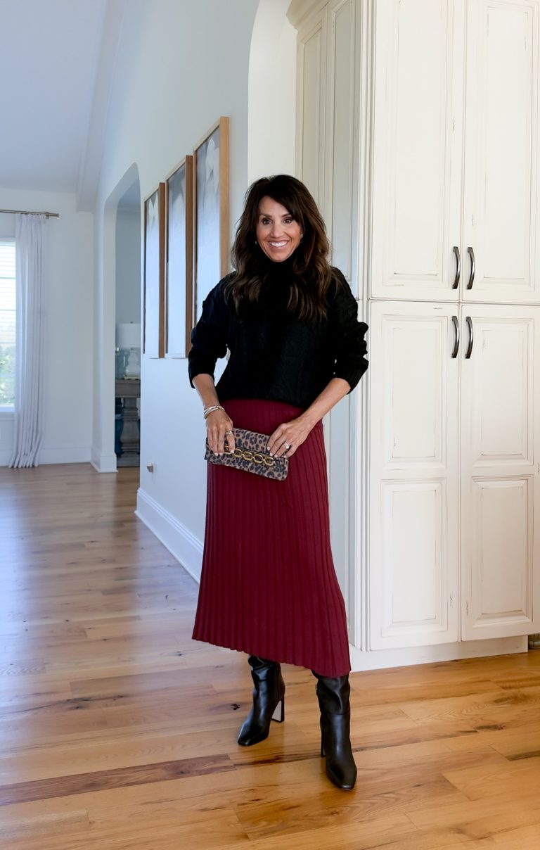 Cyndi Spivey styling a black cable-knit sweater with a burgundy midi skirt and tall black boots, showing a timeless and chic fall outfit for women over 50.