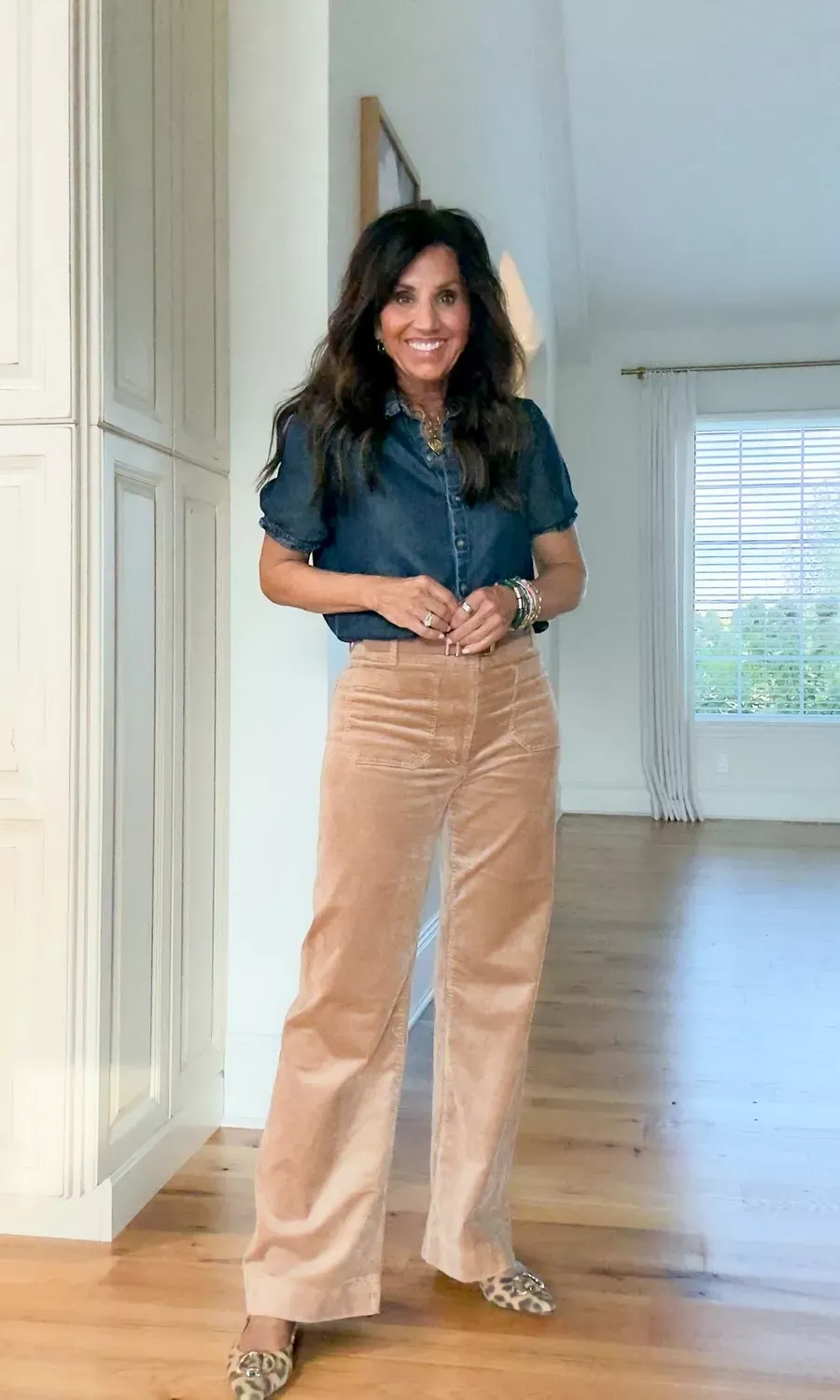 Woman over 50 wearing a pair of corduroy flare pants with a button up denim top.