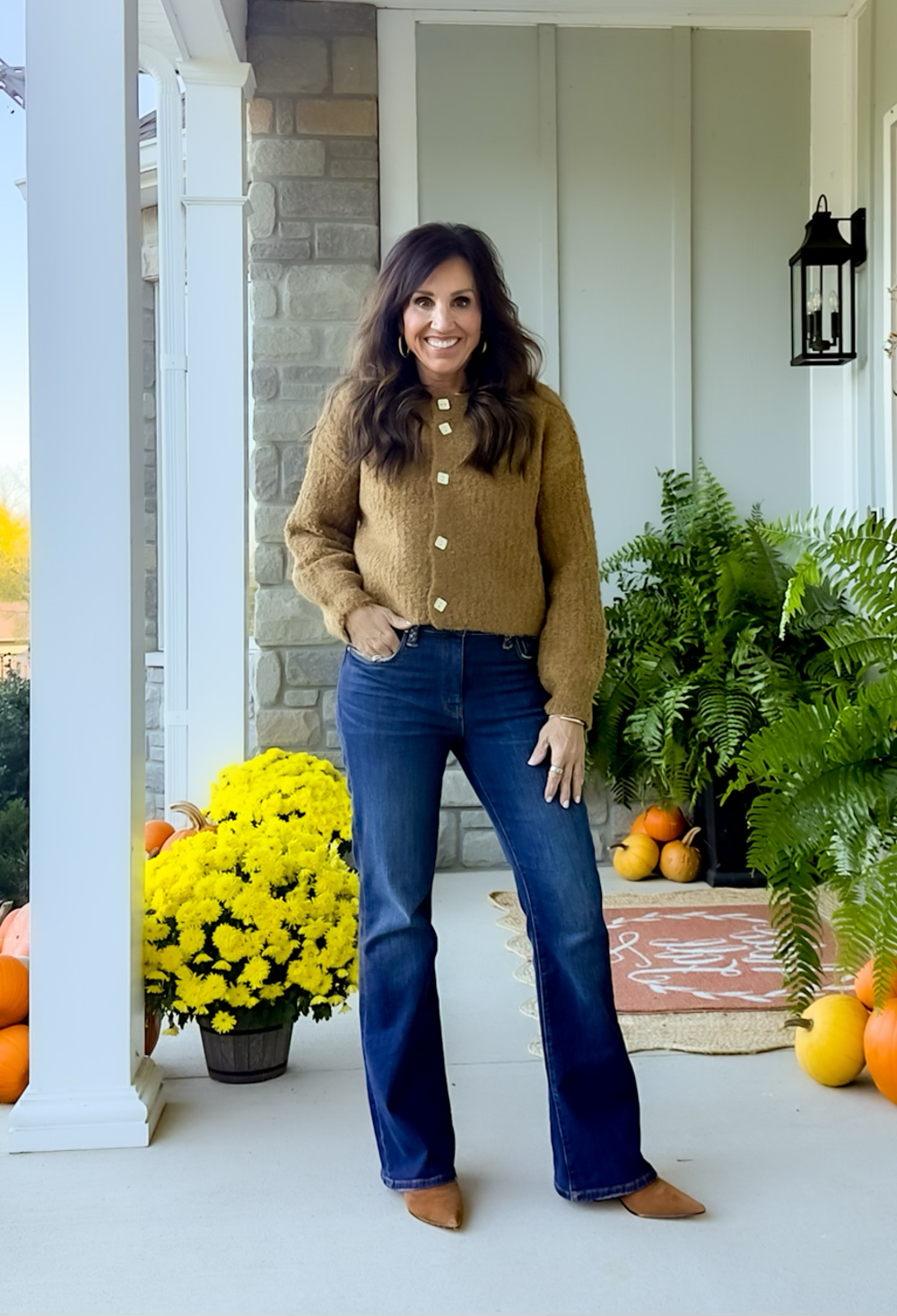 Woman wearing a caramel-colored button-up cardigan with dark jeans and brown flats, a casual Thanksgiving outfit idea for women over 50.