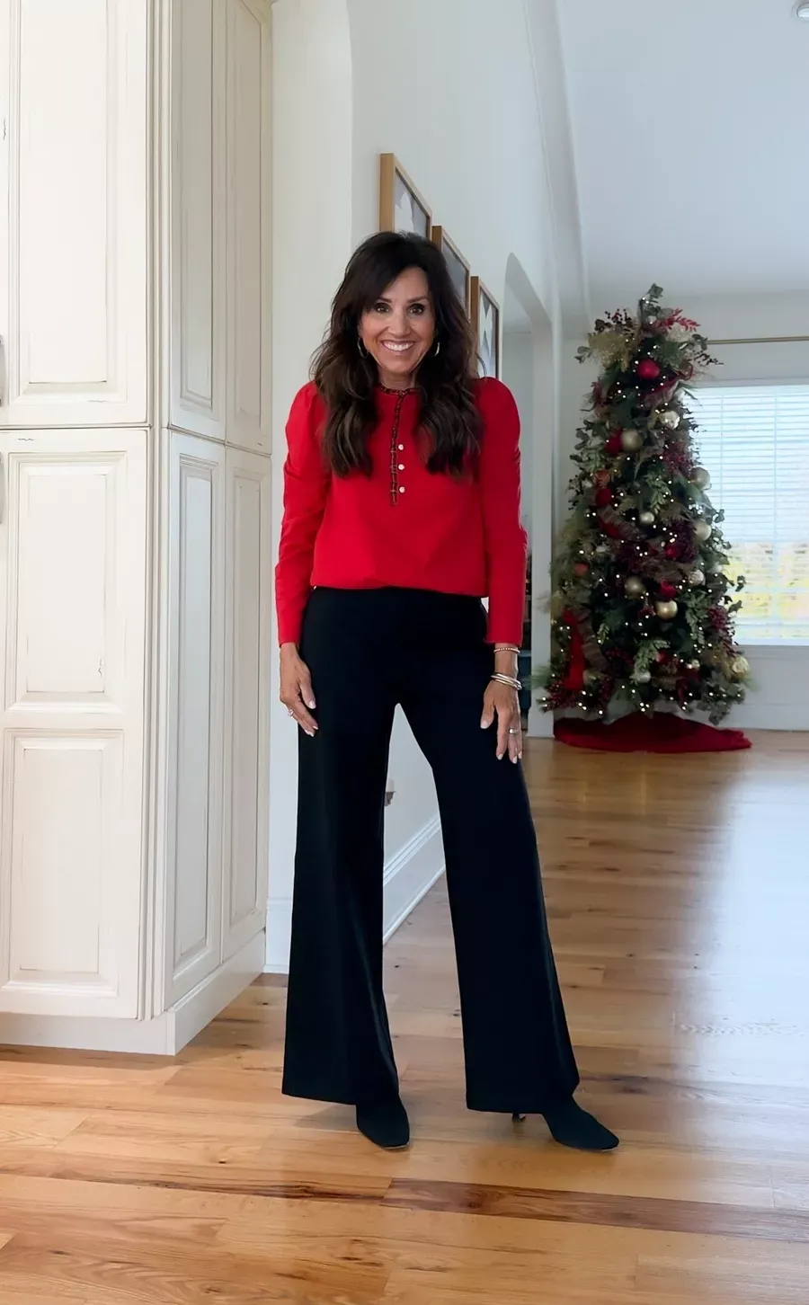 Cyndi Spivey wearing a red blouse with black wide-leg pants and heels, a timeless and festive outfit for the holidays.