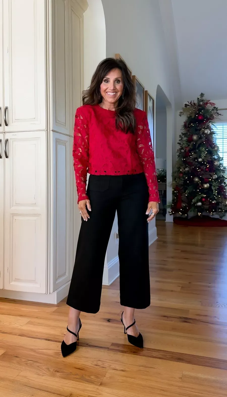 Cyndi Spivey wearing a red lace top with black cropped pants and heels, an elegant and festive holiday look.