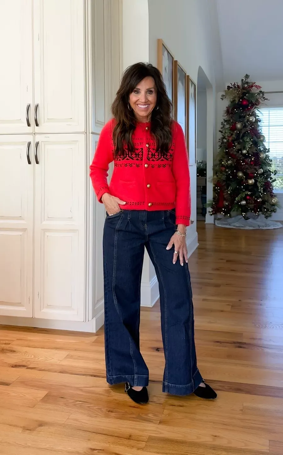 Cyndi Spivey wearing a red fair isle cardigan with dark wide-leg jeans and black flats, a cozy and classic holiday look.