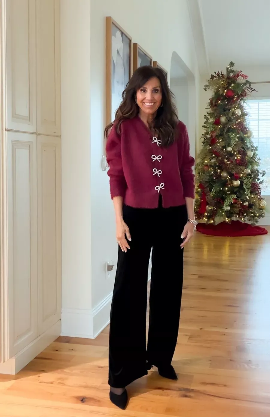 Cyndi Spivey wearing a burgundy sweater with bow details down the front and black wide-leg pants