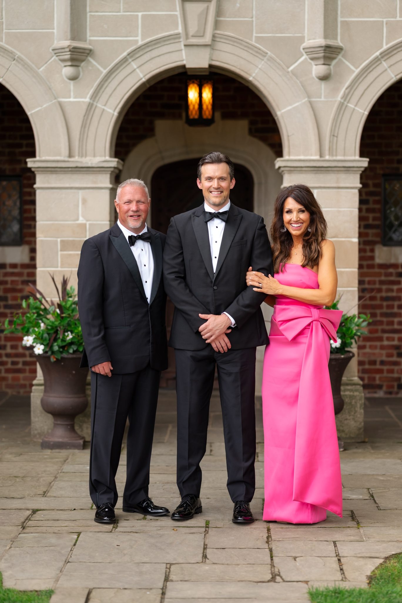 Cyndi at her son's wedding wearing a pink gown with a bow.