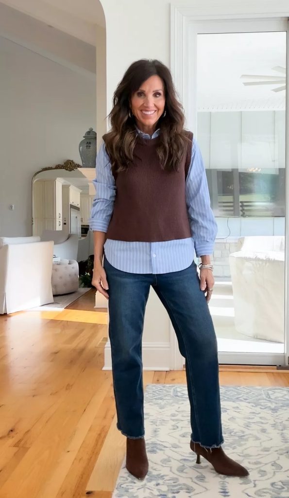 Cyndi Spivey wearing a sweater vest layered over a white button-down shirt, styled with jeans for a classic layered look.